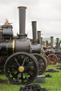 Vintage steam engines on field against sky