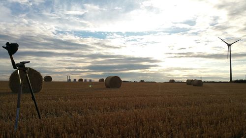 Hay bales on field against sky during sunset