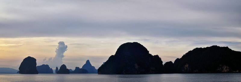 Silhouette rocks by sea against sky during sunset