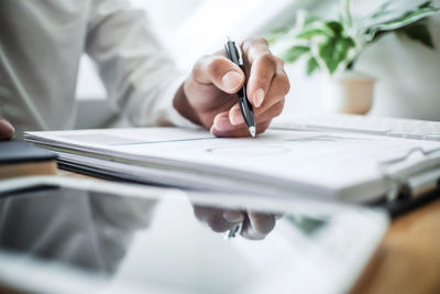 Midsection of man reading book on table