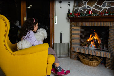 Rear view of woman sitting on sofa at home