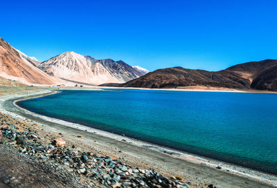 Scenic view of lake and mountains against clear blue sky