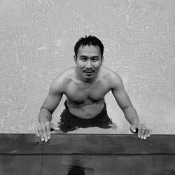 Portrait of shirtless man in swimming pool against wall