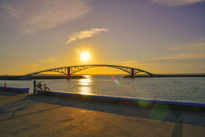 Bridge over river against sky during sunset