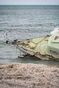 Fishing boat on sea shore against sky