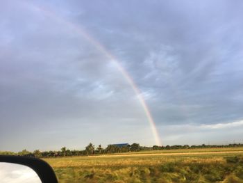 Scenic view of rainbow over field against sky