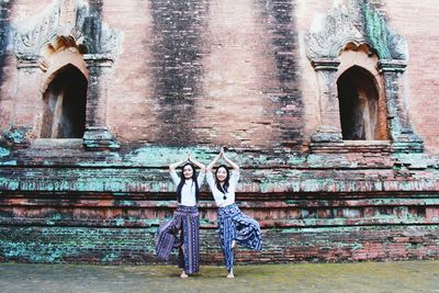 Female friends practicing tree pose against old wall