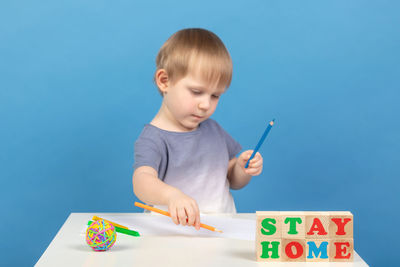 Cute boy holding toy toys against blue sky