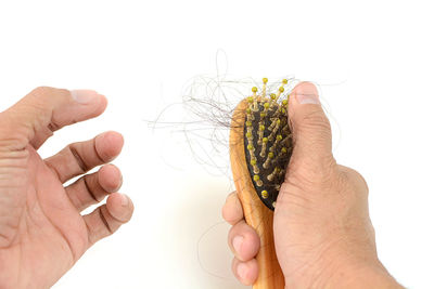 Close-up of hand holding ice cream over white background