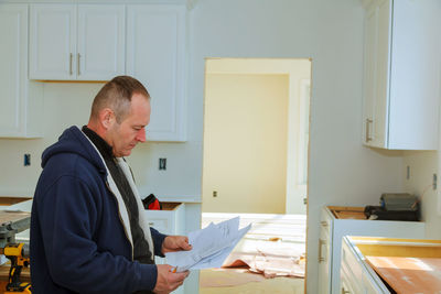 Man reading blueprint while standing at home