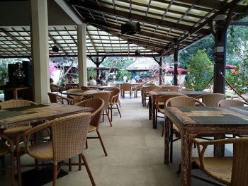 Empty chairs and tables in cafe against building