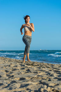 Full length of man standing on beach against clear blue sky