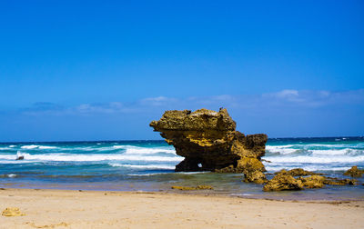 Scenic view of rock on beach against sky