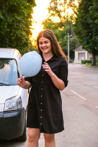 Cute and pretty young girl or student, eats and poses with sugar blue candy cotton on town street