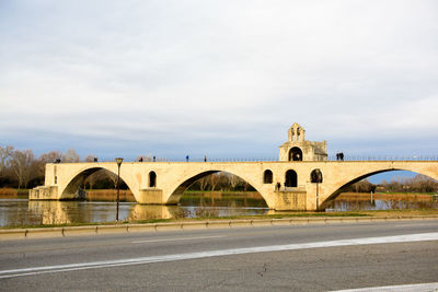 Arch bridge over river against sky in city