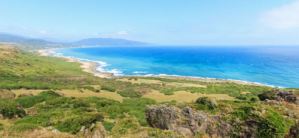 Scenic view of landscape by sea against sky