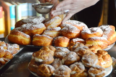 Cropped image of woman sprinkling powdered sugar on dessert