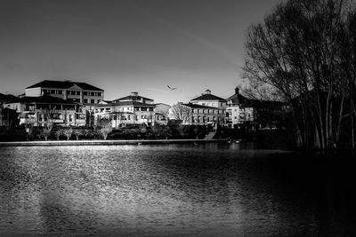 Buildings by river against sky in city
