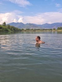 Portrait of man swimming in lake against sky