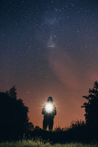 Silhouette trees on field against sky at night