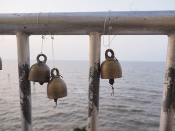 Close-up of metal hanging on rope against sea