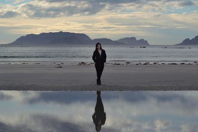 Young woman standing at beach during sunset