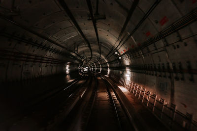 Back cabin view of driverless metro train riding through underground tunnel. 