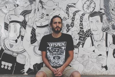 Portrait of young man sitting on wall