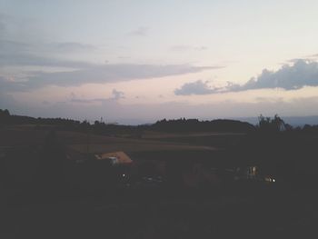 Trees on field against cloudy sky