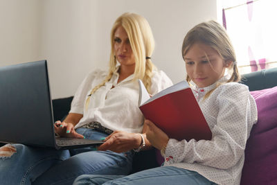 Woman using phone while sitting on laptop