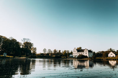Buildings by lake against clear sky