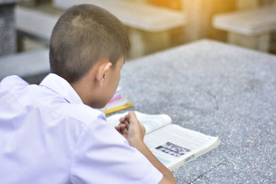 Rear view of boy holding book