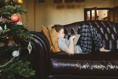 Boy using tablet pc lying on sofa at home