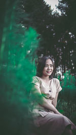 Portrait of smiling young woman sitting on land