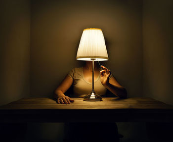 Portrait of woman with lamp on table hid head 