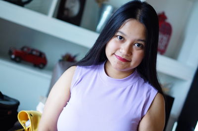 Close-up portrait of smiling young woman at home