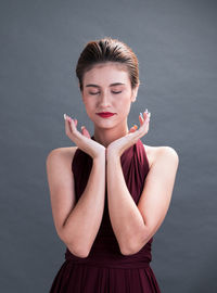 Young woman standing against gray background