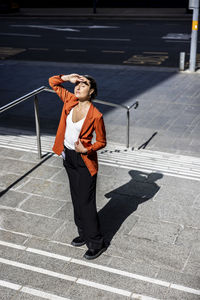 Businesswoman shielding eyes standing on staircase