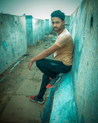 Portrait of young man sitting on wall