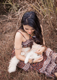 Young woman with cat sitting on grass