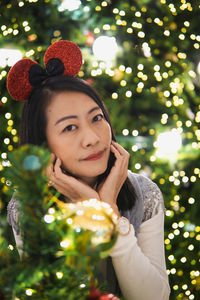 Portrait of young woman holding christmas tree