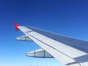 Low angle view of airplane flying against clear blue sky