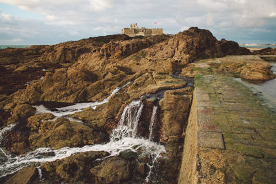 Panoramic view of cliff by sea against sky