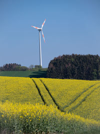 Wind turbines on field against sky