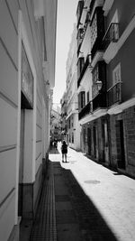 Rear view of people walking on footpath amidst buildings in city