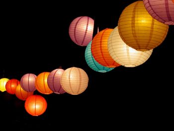 Low angle view of illuminated lanterns hanging against sky at night