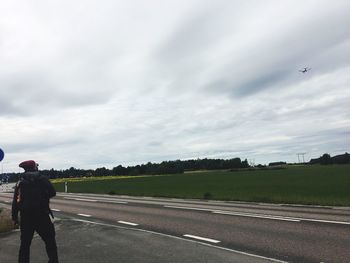 Rear view of man standing on road against sky