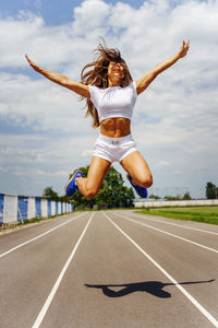 Full length of woman jumping on road