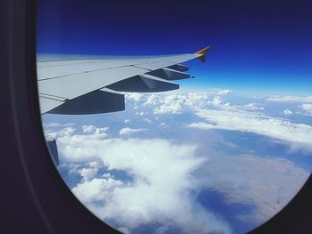 Aerial view of airplane wing over clouds