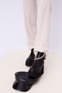 Details of trendy casual fall spring outfit. woman wearing white jeans and stylish black boots